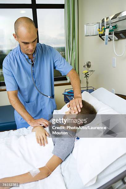 "boy lying in hospital bed, intern taking his temperature" - boy armpit stock-fotos und bilder