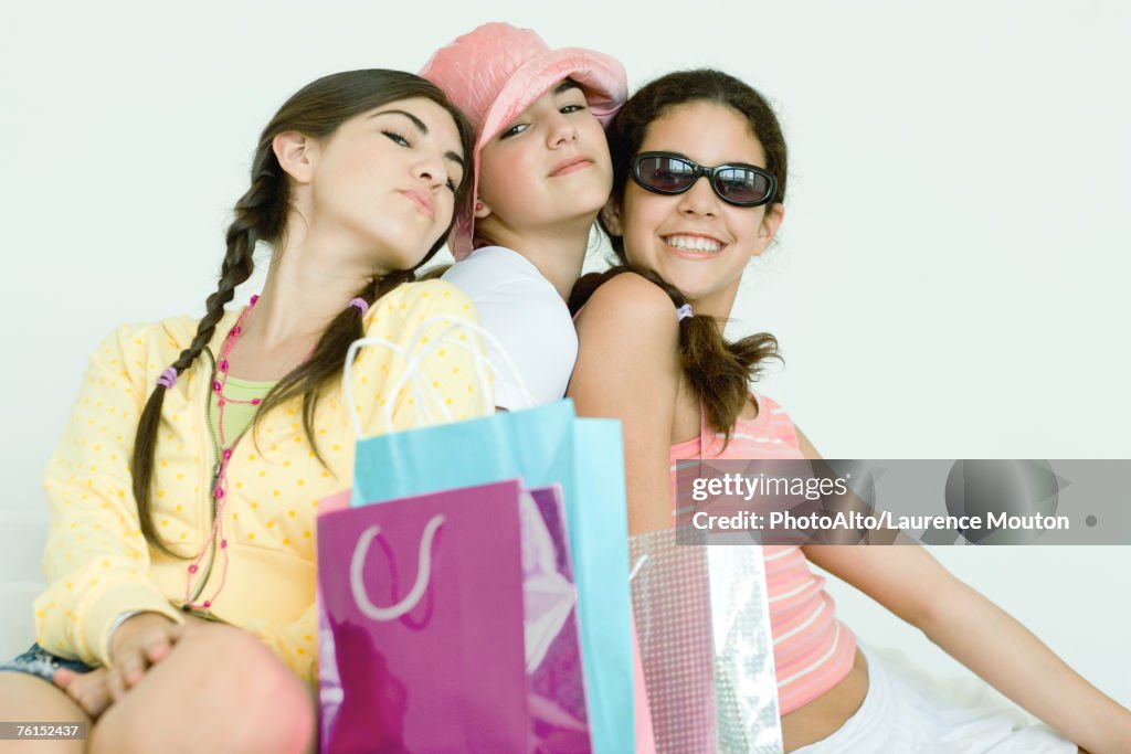 "Three young female friends posing, shopping bags in foreground"