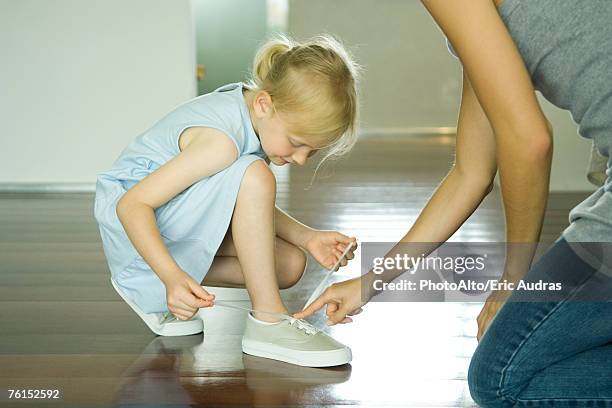 mother and daughter tying girl's shoes together - fingertier stock pictures, royalty-free photos & images