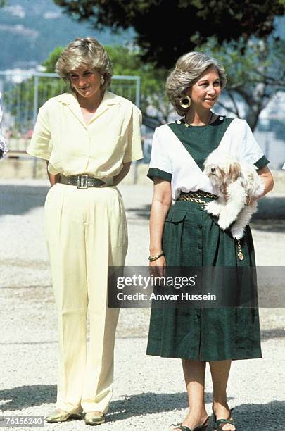 Diana, Princess of Wales, wearing a yellow jumpsuit, stands next to Queen Sofia of Spain on August 10, 1987 in Palma, Majorca.