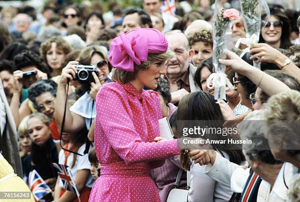 Diana, Princess of Wales, wearing a pink and white polka dot dress designed by Donald Campbell and a pink hat designed by John Boyd, is greeted by...