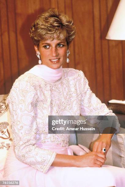 Diana, Princess of Wales, wearing a beaded evening gown with a pink chiffon sarong style detail designed by Catherine Walker, attends a dinner hosted...