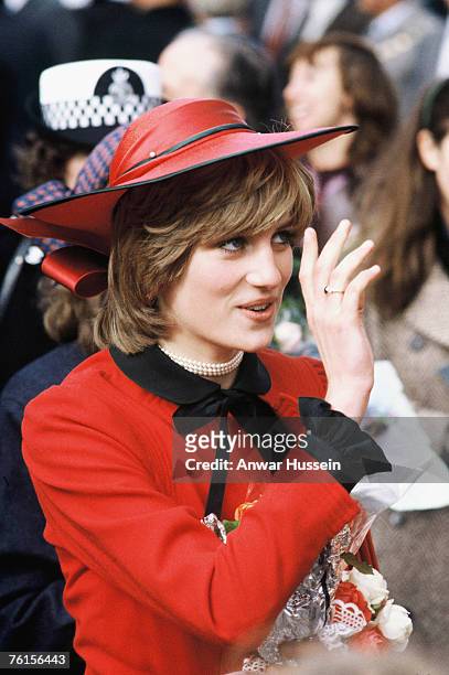 Diana, Princess of Wales, wearing a red suit with a black pleated skirt designed by Donald Campbell and a hat designed by John Boyd, is greeted by...