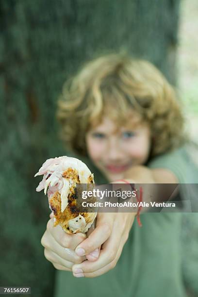 boy holding out grilled chicken leg - legale stockfoto's en -beelden