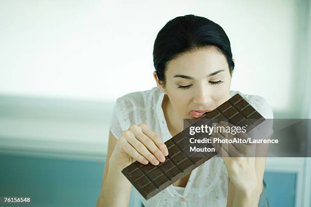 woman holding large bar of chocolate and licking lips - eating dark chocolate stock pictures, royalty-free photos & images