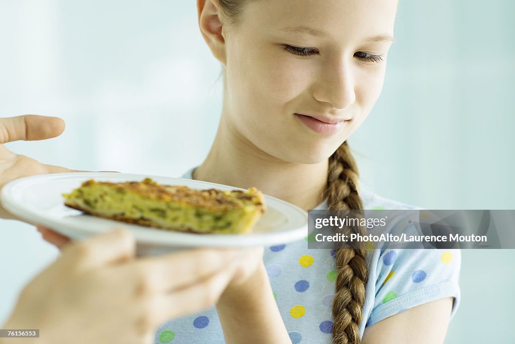 Girl making face at piece of quiche