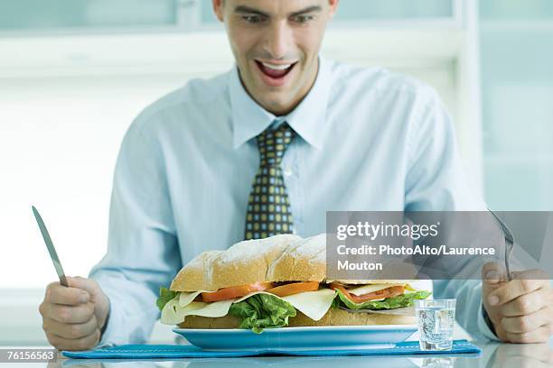 "man sitting holding knife and fork, looking down at large sandwich" - part of something bigger stock pictures, royalty-free photos & images