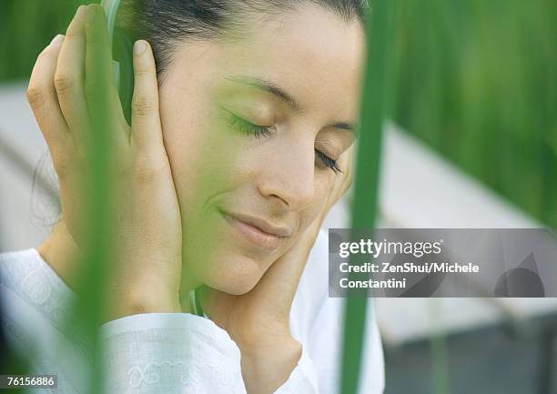 woman listening to headphones, eyes closed, hands over ears - hands over ears stock pictures, royalty-free photos & images