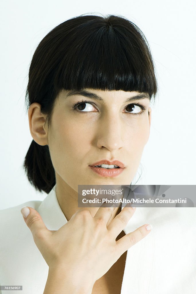 "Woman holding hand under chin, looking away, portrait"