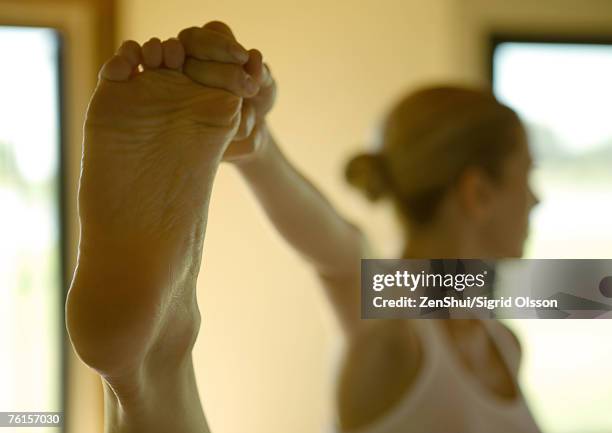 woman standing, holding up foot - bottom of feet foto e immagini stock