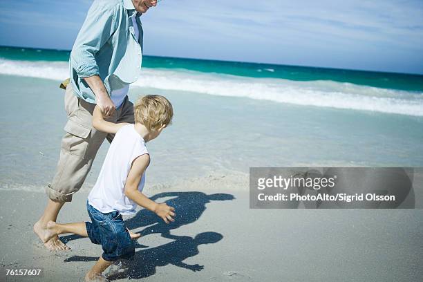 man and boy walking on beach - family no faces stockfoto's en -beelden