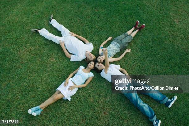 "group of young friends lying on grass, heads together" - être étendu photos et images de collection