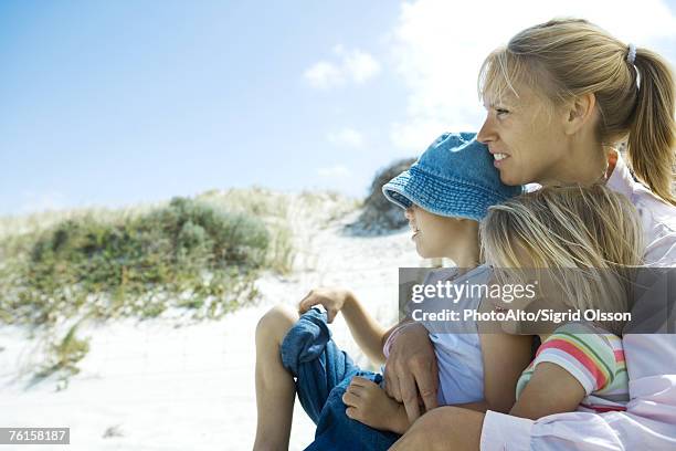 "woman holding son and daughter on lap, looking toward distance, dune in background" - blue white summer hat background stock pictures, royalty-free photos & images