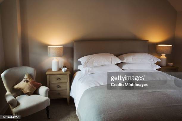 a cosy bedroom decorated in neutral colours, with a double bed and bedside lights on. hospitality.  - comfortable bedroom stock pictures, royalty-free photos & images