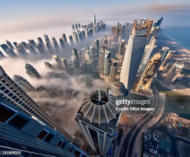 aerial view of cityscape with skyscrapers above the clouds in dubai, united arab emirates. - skyscraper foto e immagini stock