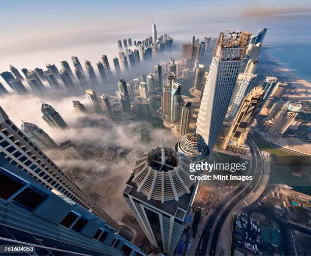 aerial view of cityscape with skyscrapers above the clouds in dubai, united arab emirates. - middle east stock pictures, royalty-free photos & images