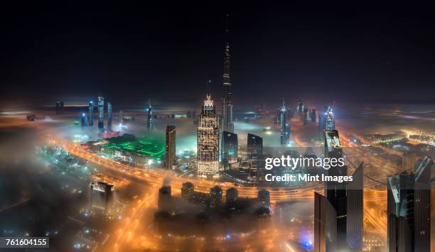 cityscape of dubai, united arab emirates with illuminated burj khalifa and other skyscrapers. - destination fashion 2016 stock pictures, royalty-free photos & images