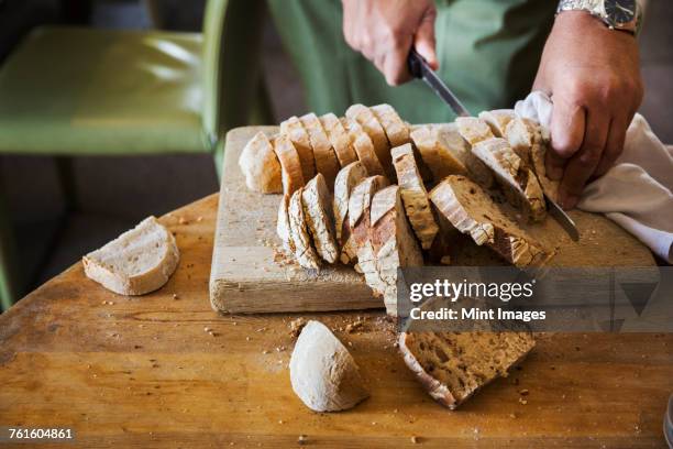 close up high angle view of person slicing freshly baked loaf of bread. - bread knife stockfoto's en -beelden