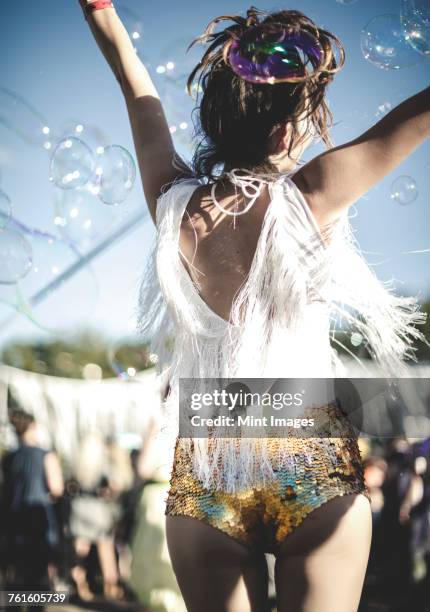 rear view of young woman at a summer music festival wearing golden sequinned hot pants, dancing among the crowd. - tarun tahiliani design launch party hosted by the directors of the british stockfoto's en -beelden