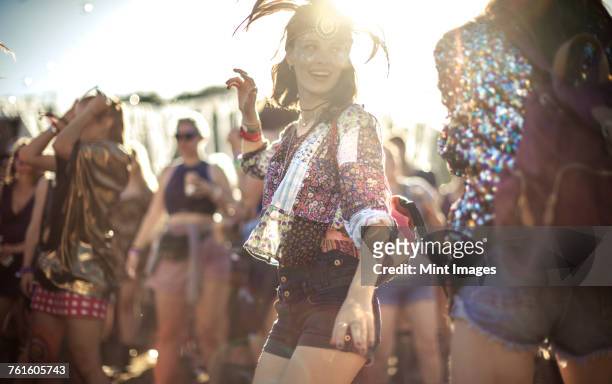 young woman at a summer music festival wearing feather headdress, dancing among the crowd. - music festival day 1 stock-fotos und bilder