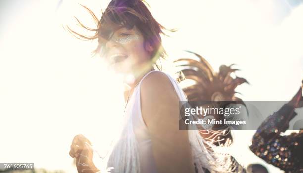 young woman at a summer music festival dancing among the crowd. - glamour stock-fotos und bilder