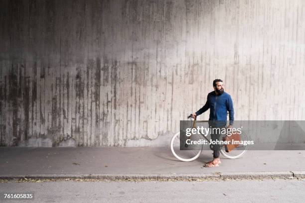 man with bicycle standing in tunnel - pedestrian walkway stock-fotos und bilder