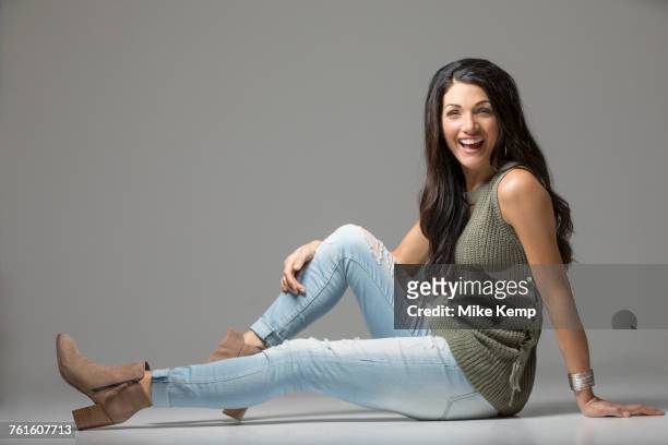 studio shot of woman sitting on floor and laughing - skinny pants stock pictures, royalty-free photos & images