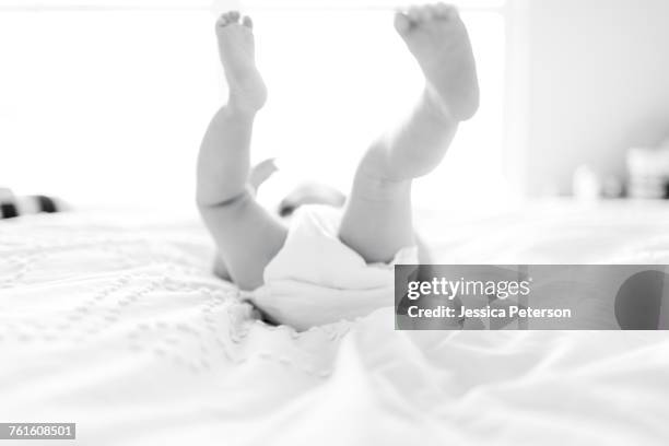 baby girl (6-11 months) lying down on bed with feet in air - barefoot feet up lying down girl stock-fotos und bilder