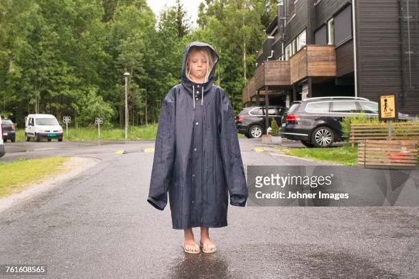 girl wearing oversized raincoat - standing in the rain girl stockfoto's en -beelden