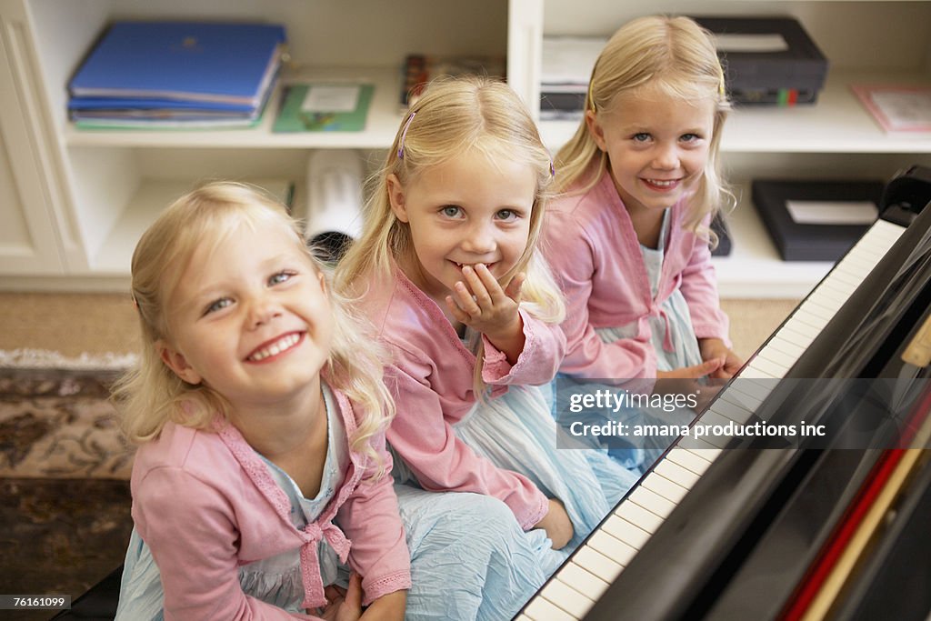 Triplets playing piano (high angle view)