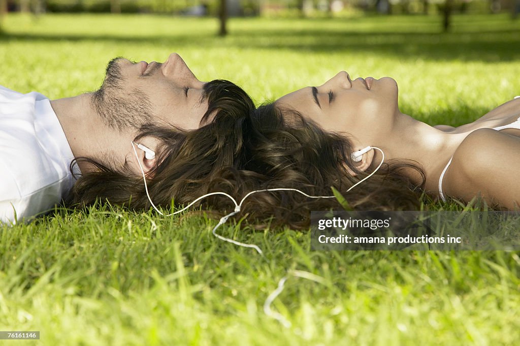 Young couple sharing MP3 player on grass