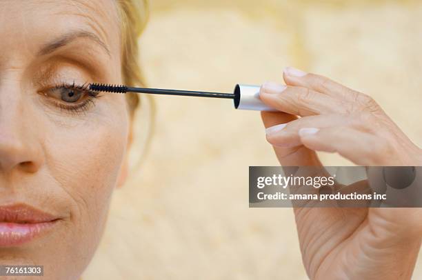 mature woman applying mascara - mascara stockfoto's en -beelden