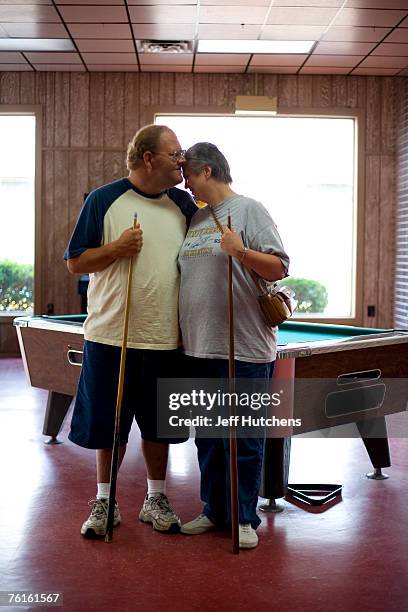 Russ Corbett and Georgia Bailey lock lips on a brief vacation while playing a game of pool and posing for a portrait in an arcade at South of the...