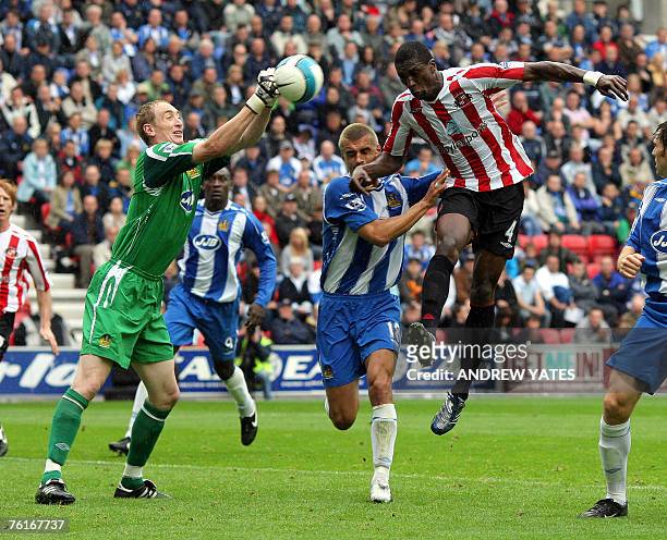 Chris Kirkland goalkeeper of Wigan Athletic punches clear from Dickson Etuhu of Sunderland and team mate Paul Scharner during the Premier league...