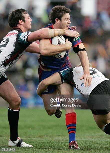 Chris Bailey of the Knights is tackled defence during the round 23 NRL match between the Newcastle Knights and the Penrith Panthers at...