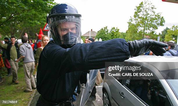 British riot police officer tries to disperse a crowd of protestors during a climate change demonstration near a British Airports Aurhority Building...
