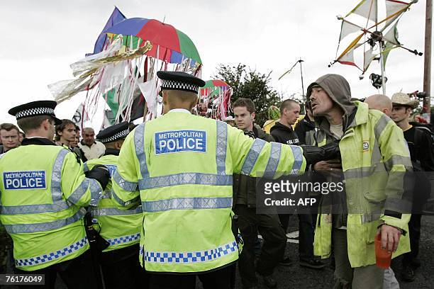 Policemen watch over protesters from the Camp For Climate Action 19 August 2007 as they leave camp to protest in nearby Harmondsworth which is at...