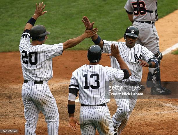 Jorge Posada, Alex Rodriguez and Robinson Cano of the New York Yankees celebrate scoring after a Wilson Betemit double in the bottom of the eighth...