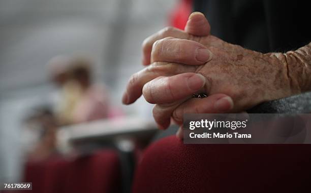 Parishioner clasps her hands in prayer during Sunday Mass at Saint Clare Catholic Church's temporary tent sanctuary August 19, 2007 in Waveland,...