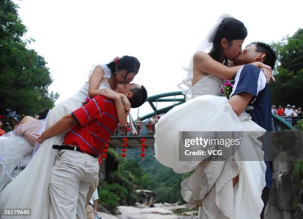 Newlyweds paricipate in a kissing contest at the foot of Huangshan Mountain in August 19, 2007 in Huangshan, China. A variety of activities were...