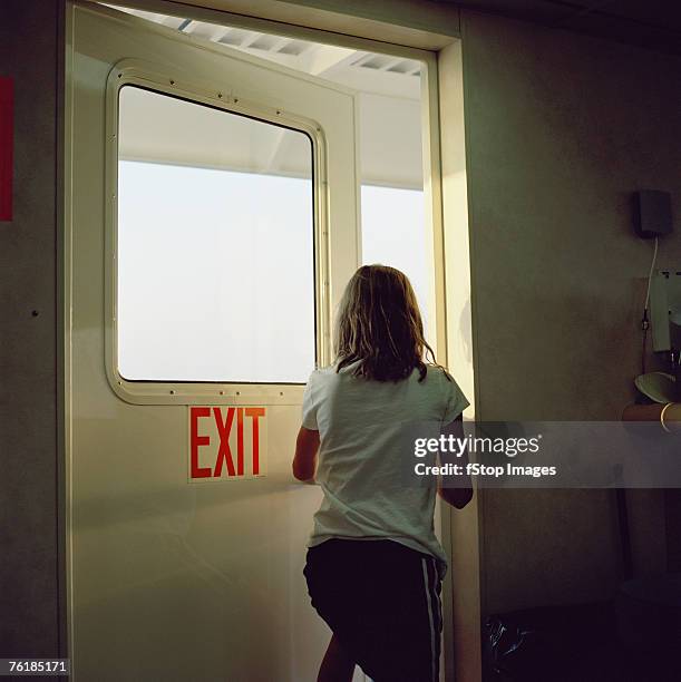 woman walking out a door - emergency exit sign stock pictures, royalty-free photos & images