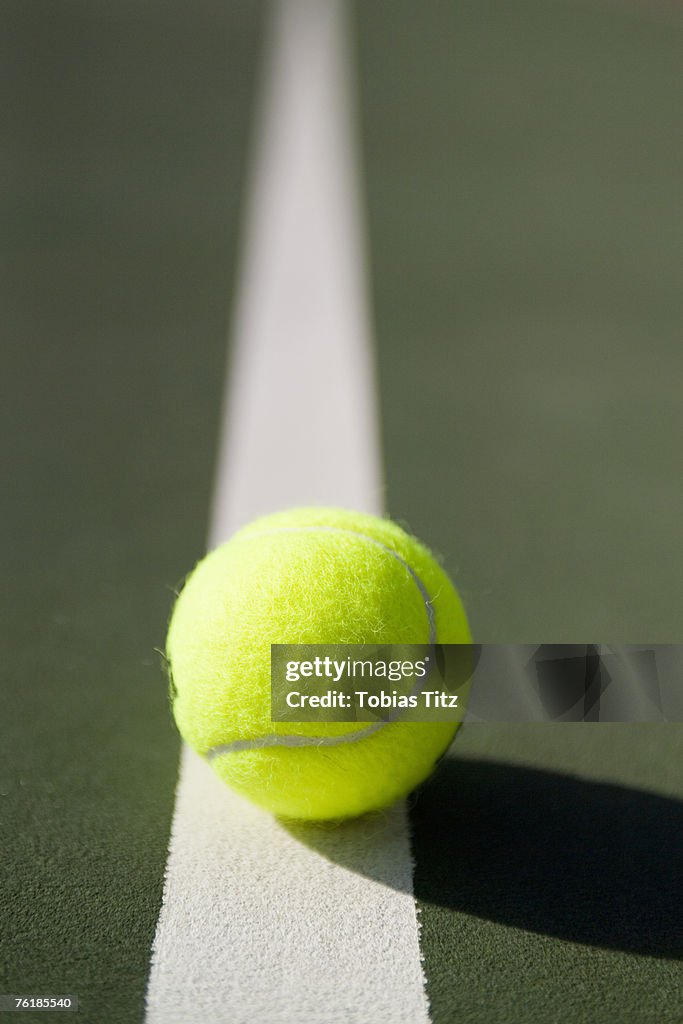 A tennis ball lying on a white line