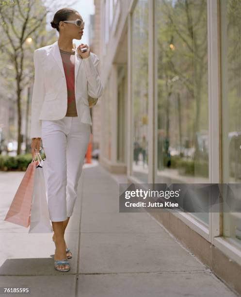 woman carrying shopping bags and looking into a shop window - window shopping stock pictures, royalty-free photos & images