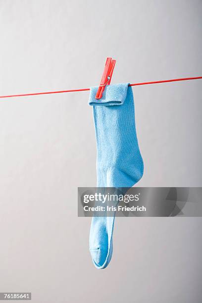 a blue sock hanging on a clothesline - waslijn stockfoto's en -beelden