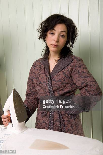 a woman holding an iron next to a burnt shirt - annoyed wife stock pictures, royalty-free photos & images
