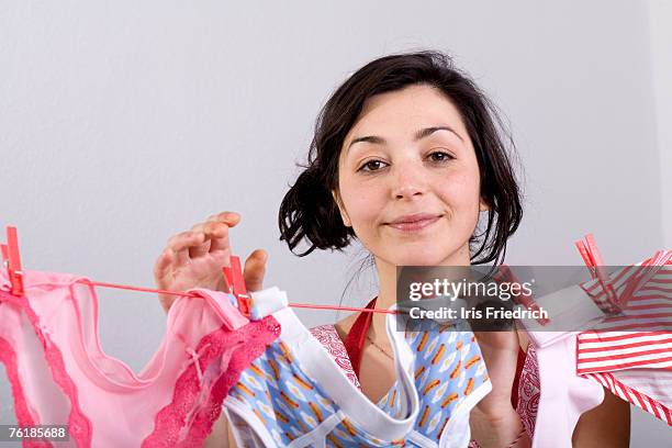 a woman hanging underwear on a clothesline - clothes peg fotografías e imágenes de stock