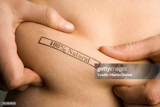 a man pinching part of his abdomen stamped '100% natural' - skin tag stock pictures, royalty-free photos & images