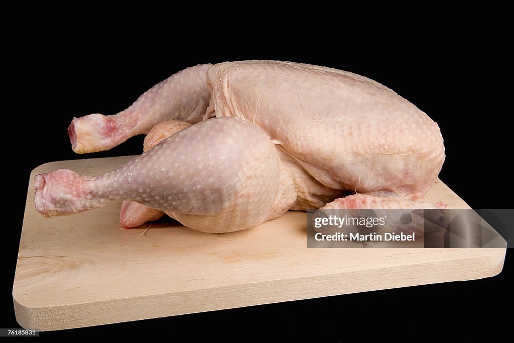 A raw chicken on a wooden cutting board