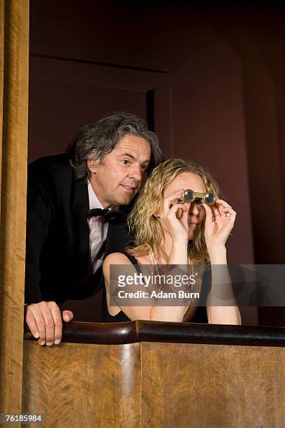 a couple using binoculars in a theater box - opera box photos et images de collection