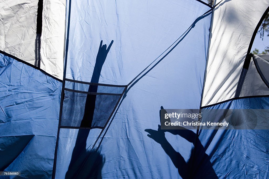 Children making shadow puppets behind a tent